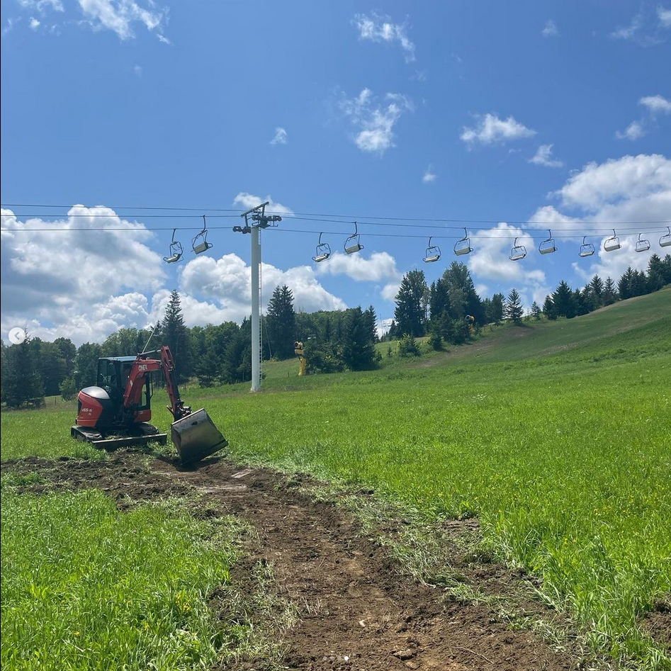 Mini excavator on skill hill digging climb trail